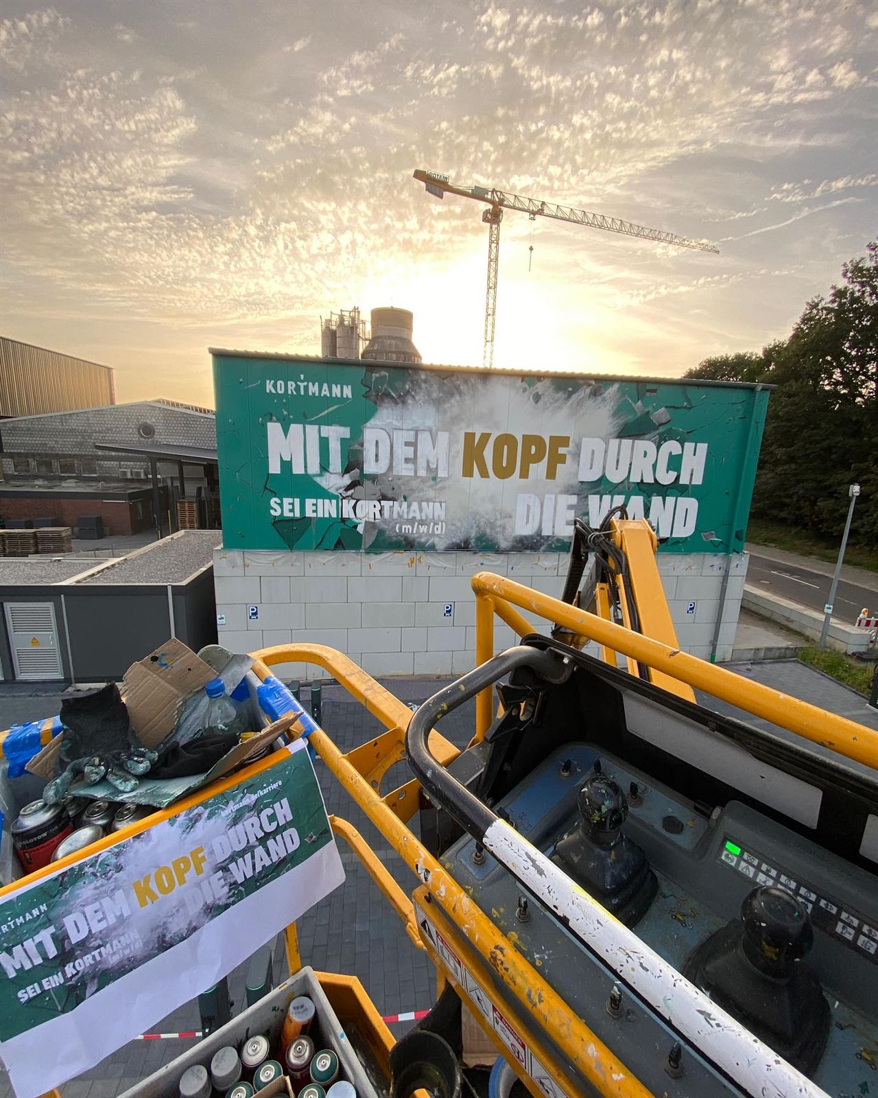 Arbeiten von der Hebebühne aus an der Kortmann-Imagewand „Mit dem Kopf durch die Wand“